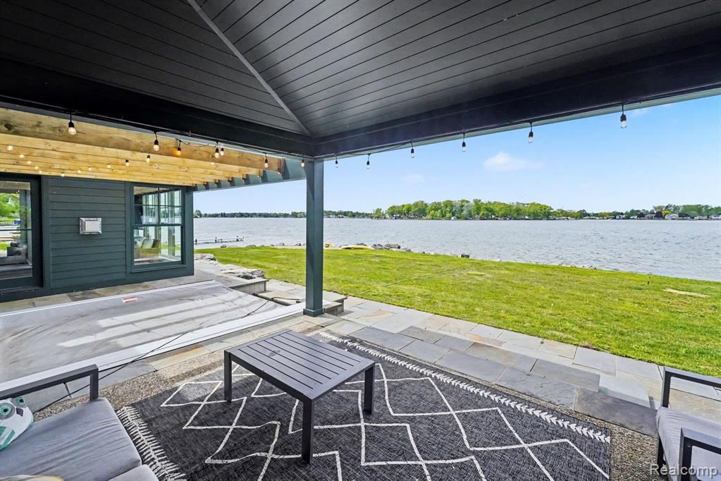 Covered patio with outdoor seating and a view of the lake